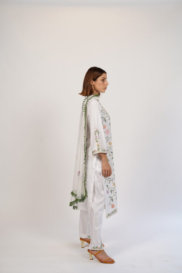 Side profile of VaadiByLiza’s white floral Aari-embroidered kurta set with colorful floral detailing and chiffon dupatta.