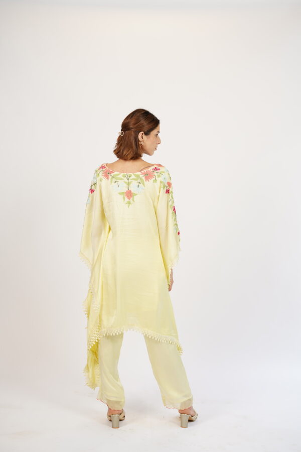 Back view of a pastel yellow silk kaftan with floral embroidery, showcasing the intricate design.