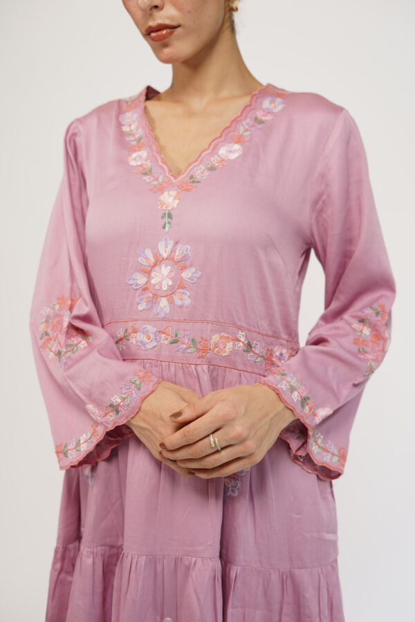 Close-up of a lavender pink tiered maxi dress with intricate floral embroidery on the neckline and sleeves.